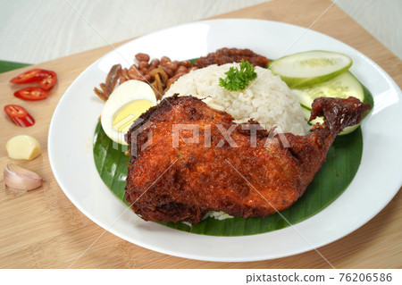 Nasi Lemak dish with chicken drum stick presented on wooden chopping board 76206586
