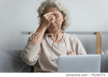 Mature pensioner tired of working at laptop from home 76206771