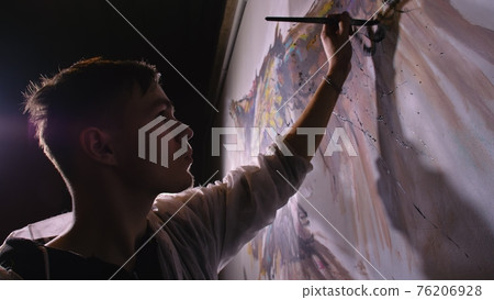 Artist designer draws an eagle on the wall. Craftsman decorator paints picture with acrylic oil color. Painter painter dressed in paint coat. Indoor. Artist designer draws an eagle on the wall. Craftsman decorator paints picture with acrylic oil color. Painter painter dressed in paint coat. Indoor. 76206928