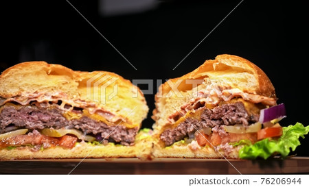 Cut craft burger is cooking on black background. Consist: sauce, lettuce, tomato, red onion, pickle, cheese, bacon, air bun and marbled meat beef. Cut craft burger is cooking on black background. Consist: sauce, lettuce, tomato, red onion, pickle, cheese, bacon, air bun and marbled meat beef. 76206944