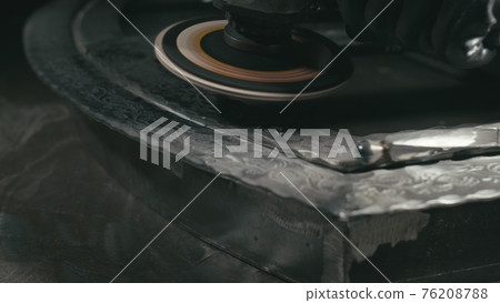 Forge workshop. Smithy manual production. Polish metal with an angle grinder with an abrasive nozzle. Polishing iron. 76208788