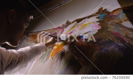 Artist designer draws an eagle on the wall. Craftsman decorator paints picture with acrylic oil color. Painter painter dressed in paint coat. Indoor. Artist designer draws an eagle on the wall. Craftsman decorator paints picture with acrylic oil color. Painter painter dressed in paint coat. Indoor. 76208890