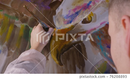 Artist designer draws an eagle on the wall. Craftsman decorator paints a picture with acrylic oil color brush. Close-up dark magic cinematic look. Artist designer draws an eagle on the wall. Craftsman decorator paints a picture with acrylic oil color brush. Close-up dark magic cinematic look. 76208893