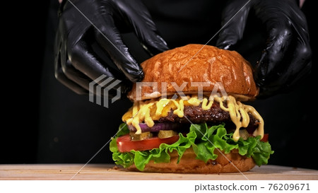 Craft burger is cooking on black background. Consist: sauce, lettuce, tomato, red onion, pickle, cheese, bacon, air bun and marbled meat beef. 76209671