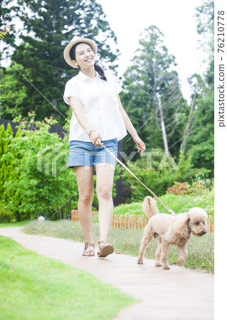 A woman walking with a dog 76210778