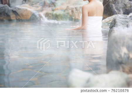 A woman bathing in an open-air bath 76210876