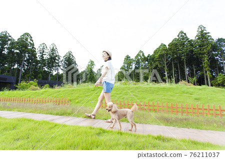 A woman walking with a dog 76211037