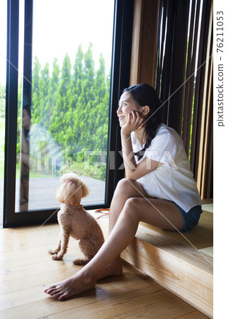 A woman relaxing in a cottage with a dog A woman relaxing in a cottage with a dog 76211053