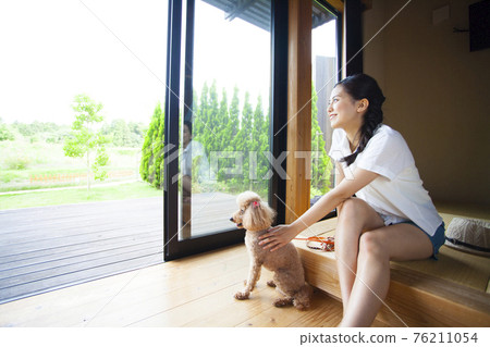 A woman relaxing in a cottage with a dog 76211054