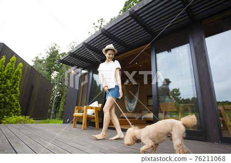 Woman playing with a dog on the wooden deck of the cottage Woman playing with a dog on the wooden deck of the cottage 76211068