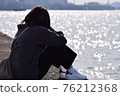 A woman sitting at the beach and thinking 76212368