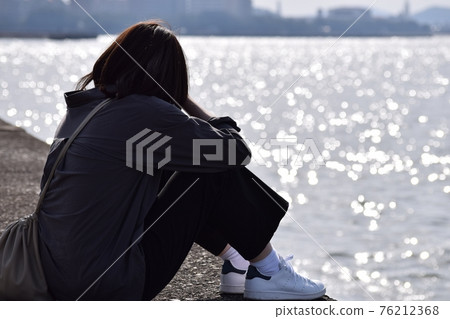 A woman sitting at the beach and thinking A woman sitting at the beach and thinking 76212368