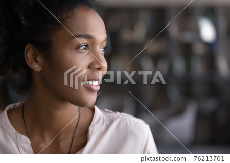 Smiling young biracial woman look in distance dreaming 76213701