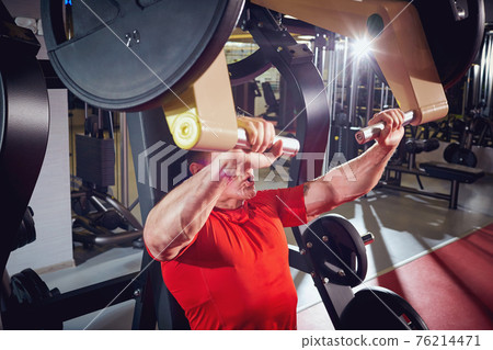 Man sports doing exercise on simulator in the gym Man sports doing exercise on simulator in the gym 76214471
