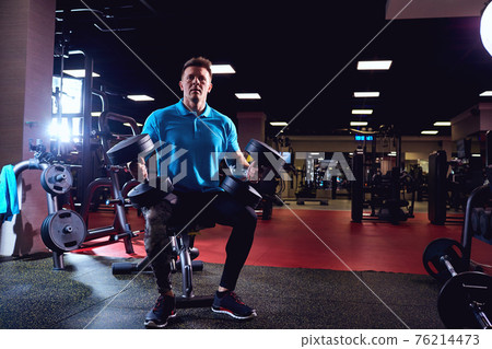 Muscular man with dumbbells in the gym Muscular man with dumbbells in the gym 76214473
