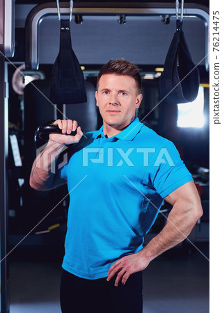 A sporty male with weights of dumbbells in his hand the gym A sporty male with weights of dumbbells in his hand the gym 76214475