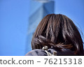 A woman looking up at a building under the blue sky 76215318