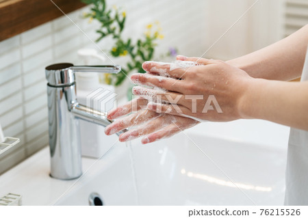 Woman washing hands in the bathroom 76215526