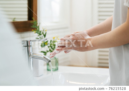 Woman washing hands in the bathroom 76215528