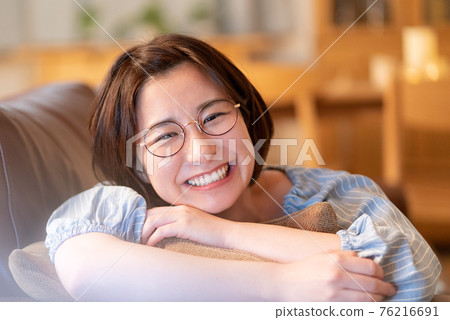 面對一位年輕女子躺在客廳的沙發上大笑 76216691
