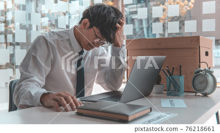 Businessman held his temple with his hand and had a brown document box beside it, Businessmen hand in resignation papers and packing office supplies in boxes with regret or disappointment. Businessman held his temple with his hand and had a brown document box beside it, Businessmen hand in resignation papers and packing office supplies in boxes with regret or disappointment. 76218661