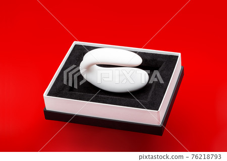 vibrator silicone curved white color in black box intimate gift sex toy for couple, erotic gadget for adults on red background with shadow, nobody. 76218793
