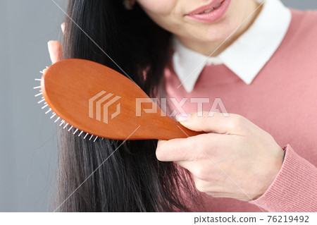 Brunette woman combs her hair with wooden comb 76219492
