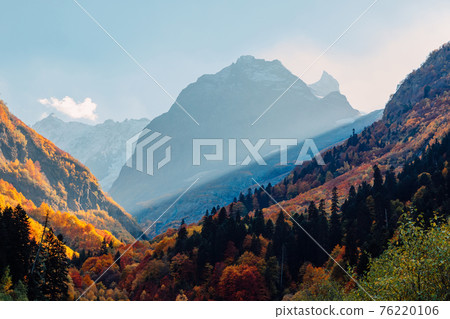 Rocky mountains and autumnal forest. High mountain landscape and amazing sun rays Rocky mountains and autumnal forest. High mountain landscape and amazing sun rays 76220106