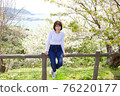 一個女人在櫻花和大海的背景下爬籬笆 76220177