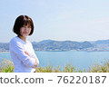 在大海和山脈的背景下，一個女人雙臂交叉的照片 76220187