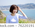 一個女人在大海和綠色背景下擠壓她的頭髮 76220191