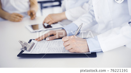 Unknown woman-doctors at work consulting patient. Female physicians filling up medical documents or prescription, close-up. Health care concept Unknown woman-doctors at work consulting patient. Female physicians filling up medical documents or prescription, close-up. Health care concept 76221191