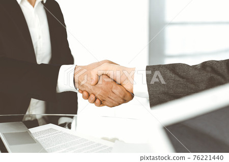 Unknown diverse business people are shaking hands finishing up meeting at the desk in office, close-up. Handshake concept 76221440