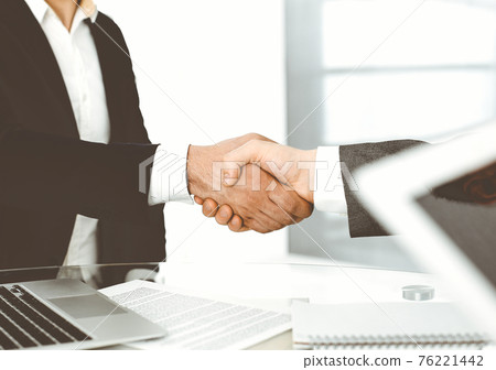 Unknown diverse business people are shaking hands finishing up meeting at the desk in office, close-up. Handshake concept 76221442