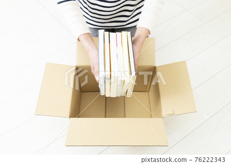 Woman packing books in cardboard 76222343
