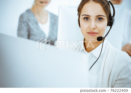 Call center. Group of diverse operators at work. Beautiful woman in headset communicating with customers of telemarketing service. Business concept 76222409