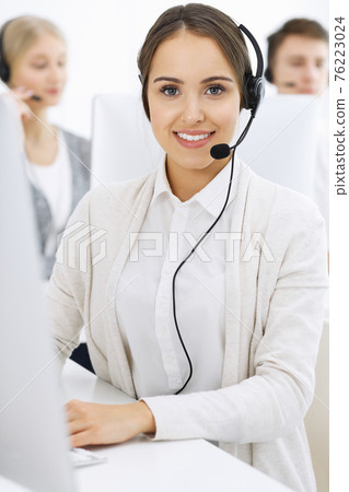 Call center. Group of diverse operators at work. Beautiful woman in headset communicating with customers of telemarketing service. Business concept Call center. Group of diverse operators at work. Beautiful woman in headset communicating with customers of telemarketing service. Business concept 76223024