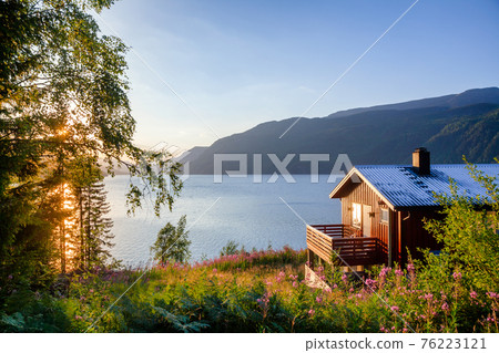 Wooden summerhouse with terrace overlooking scenic lake at sunset in Norway Scandinavia Wooden summerhouse with terrace overlooking scenic lake at sunset in Norway Scandinavia 76223121