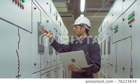 An engineer man or worker, people using a laptop computer, working in electrical room. Power energy motor machinery cabinets in control or server room, operator station network in industry factory. An engineer man or worker, people using a laptop computer, working in electrical room. Power energy motor machinery cabinets in control or server room, operator station network in industry factory. 76223634