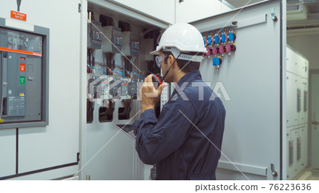 An engineer man or worker, people using a laptop computer, working in electrical room. Power energy motor machinery cabinets in control or server room, operator station network in industry factory. 76223636
