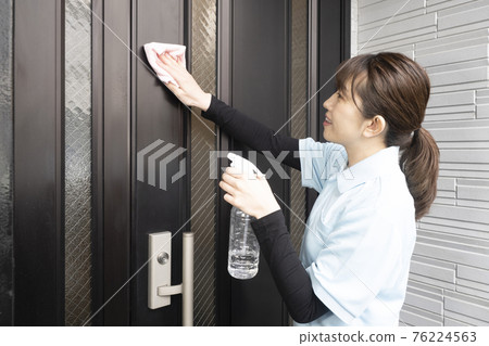 House cleaning woman wiping the front door 76224563