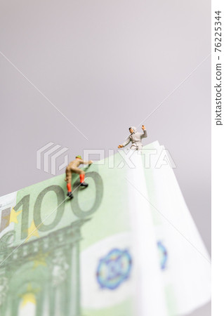 Miniature people , climber climbs on a EURO banknote Miniature people , climber climbs on a EURO banknote 76225344