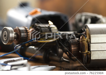 Burning wires on the details of an electrical appliance on a wooden table in a repair shop. Power tool repair Burning wires on the details of an electrical appliance on a wooden table in a repair shop. Power tool repair 76225984
