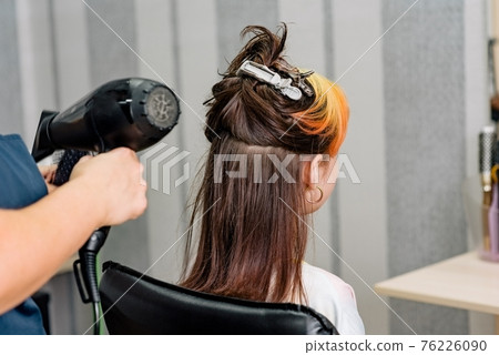 The hairdresser dyes the hair of the girl in the beauty salon. Fashion dyed bleached bangs 76226090