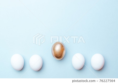 Easter gold. Golden, white colour egg on pastel blue background in Happy Easter decoration. Traditional design in top view. Easter gold. Golden, white colour egg on pastel blue background in Happy Easter decoration. Traditional design in top view. 76227564