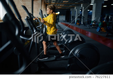Child on exercise machine, training in gym Child on exercise machine, training in gym 76227811