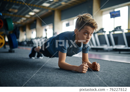 Boy doing push up exercise on the floor in gym Boy doing push up exercise on the floor in gym 76227812