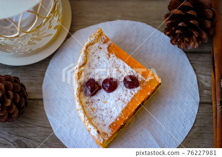 A piece of sweet pie made of cottage cheese and pumpkin, sprinkled on top with powdered sugar 76227981