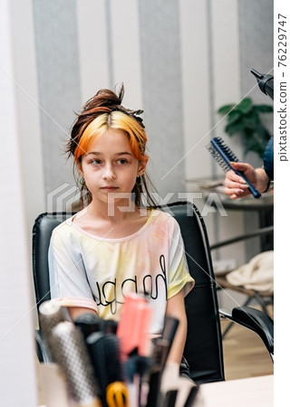 The hairdresser dyes the hair of the girl in the beauty salon. Fashion dyed bleached bangs 76229747