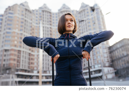 Young sporty woman doing exercises with rubber band outdoor Young sporty woman doing exercises with rubber band outdoor 76230074